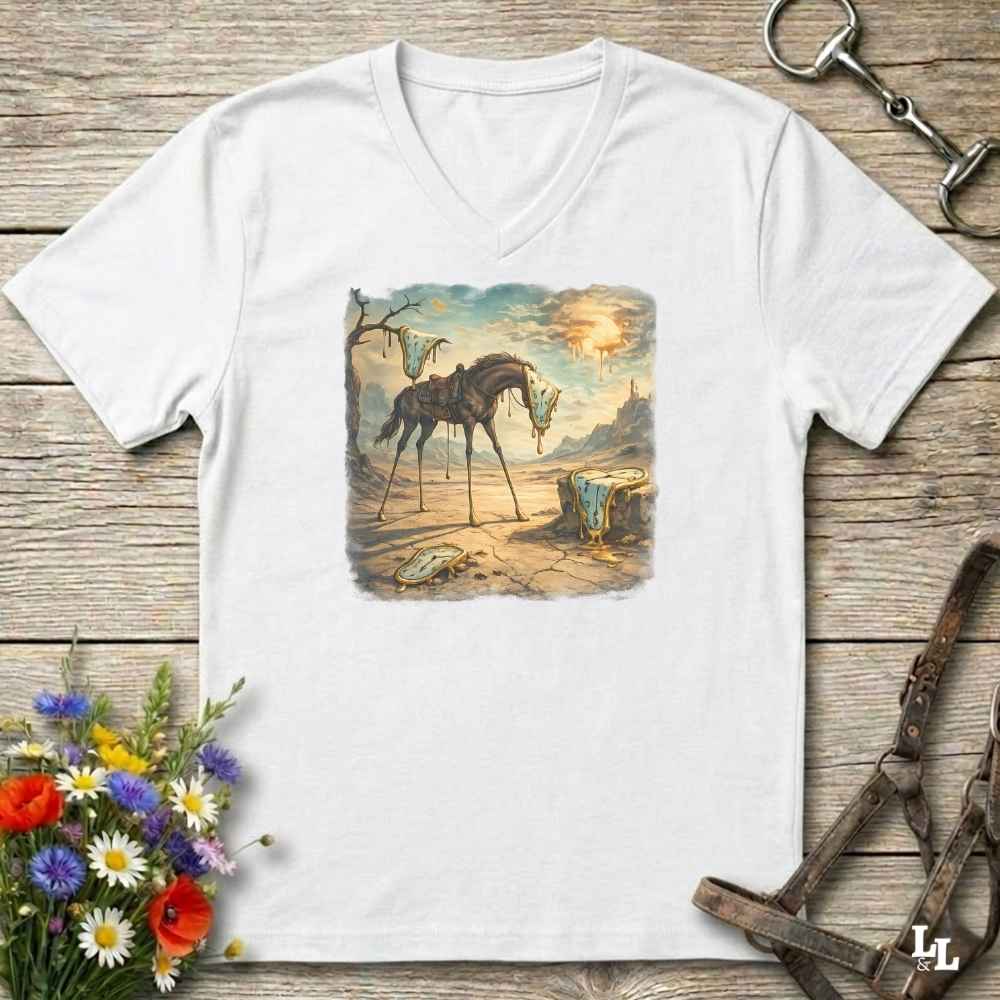 A white V-neck t-shirt laid flat on a rustic wooden surface, featuring a vintage-style equestrian art print on the chest. The print depicts a dark horse standing in a dusty landscape under a glowing sun.