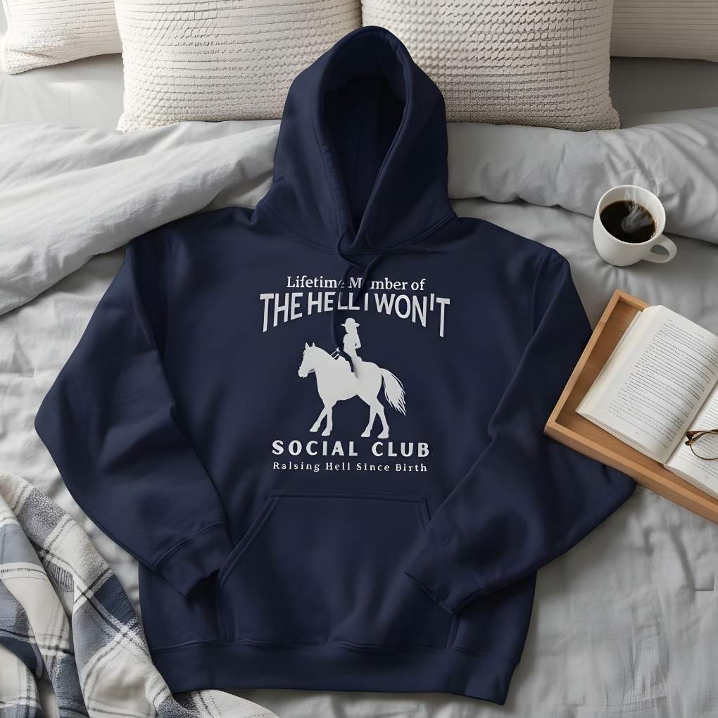 Navy blue hoodie with humorous text and graphic on a bed with pillows and a cup of coffee. The Hell I Won't Hoodie for Horse Lovers, Cowgirl Sweatshirt Horse Riding Apparel