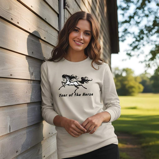 Woman wearing a white sweatshirt with a horse graphic and text, standing against a wooden wall. Year of the Horse Long Sleeve Tee for Horse Lovers, Riding Apparel Equestrian Wear