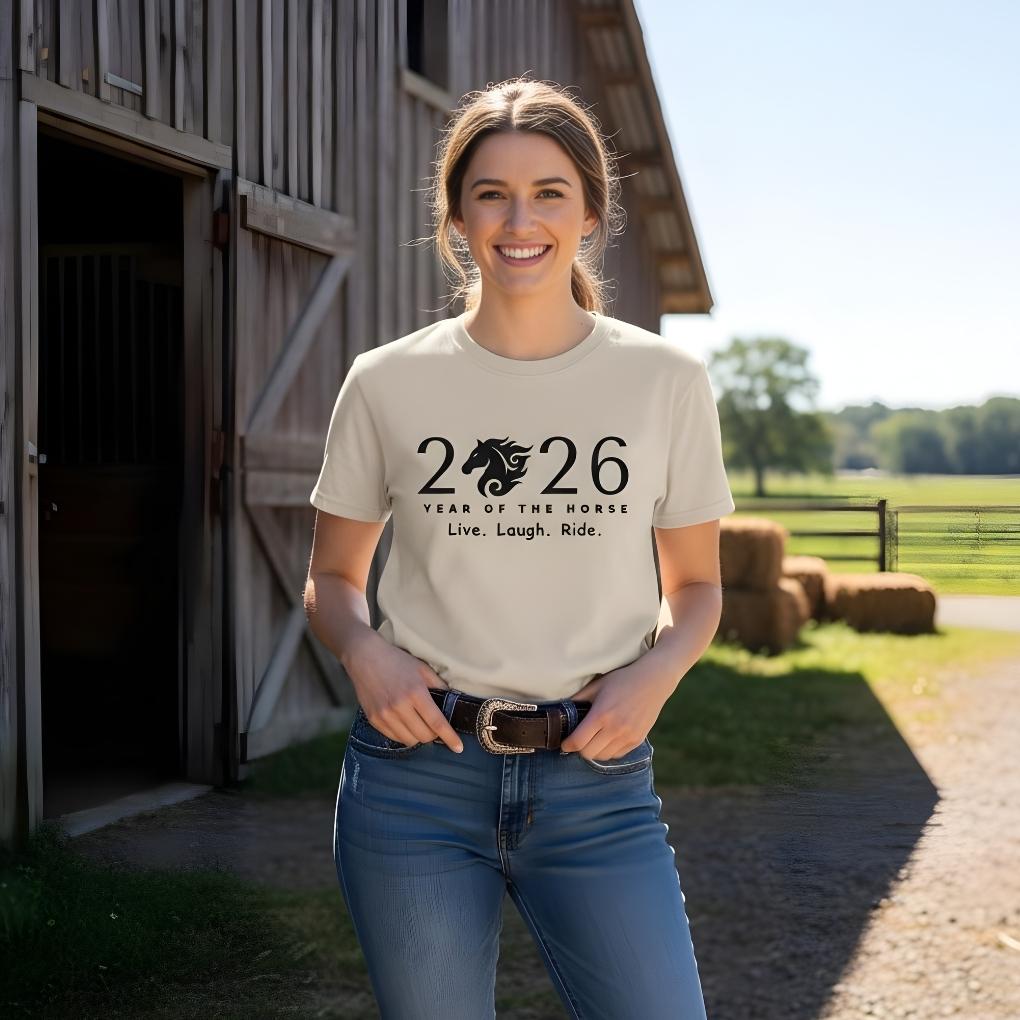 Woman wearing a t-shirt with '2026 Year of the Horse' design in front of a barn. Live Laugh Ride T-Shirt for Horse Lovers, Riding Apparel, Barn Wear Tee