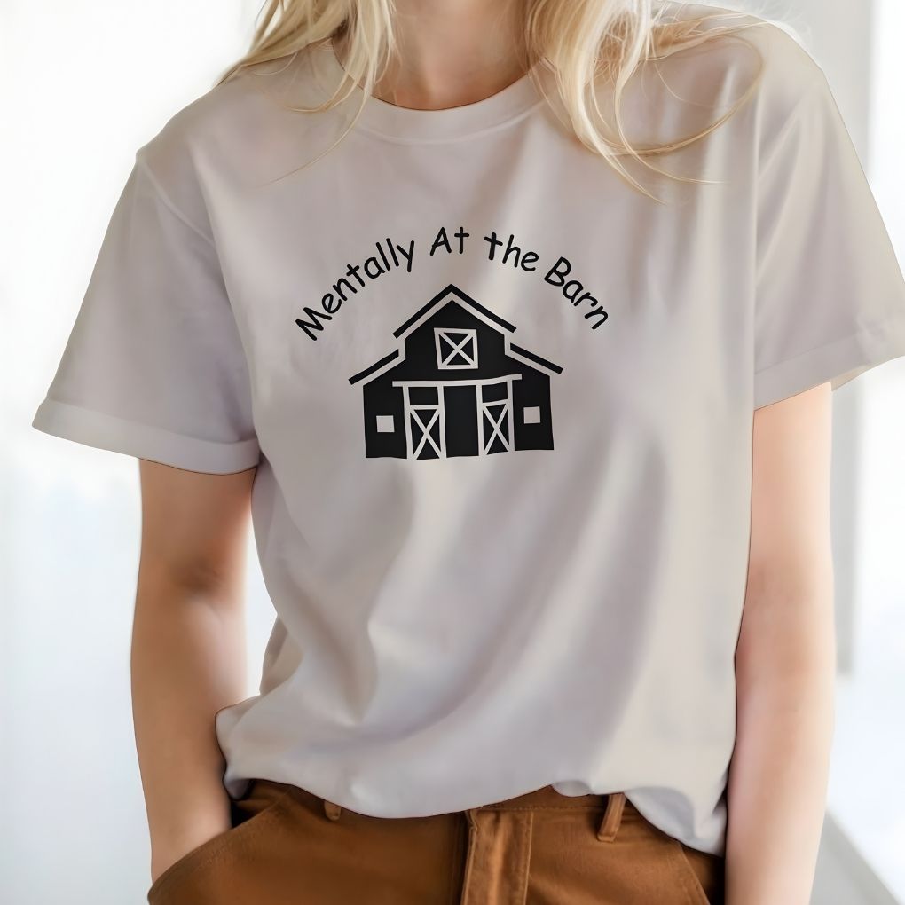 White t-shirt with a barn graphic and text worn by a person on a white background. Mentally at the Barn T-Shirt for Horse Lovers, Riding Tee Barn Wear Tee