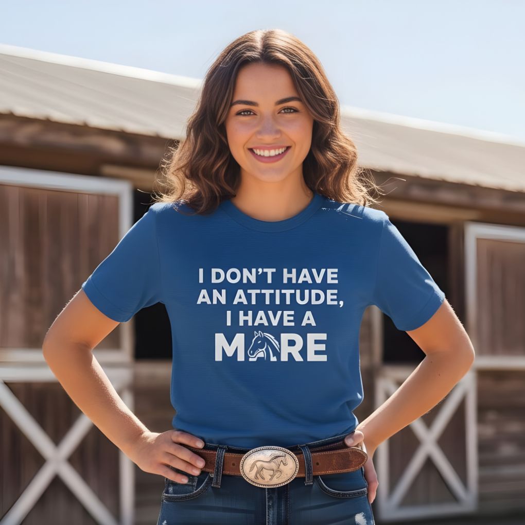 Woman wearing a blue t-shirt with text standing in front of a wooden building. I Don't have an Attitude T-Shirt for Horse Lovers, Barn Wear Tee, Trail Riding Tee