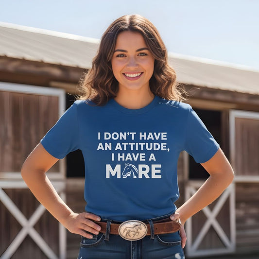 Woman wearing a blue t-shirt with text standing in front of a wooden building. I Don't have an Attitude T-Shirt for Horse Lovers, Barn Wear Tee, Trail Riding Tee
