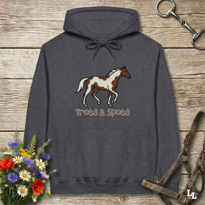 Gray hoodie with horse design and 'Trots & Spots' text on a wooden surface with floral and equestrian accessories.