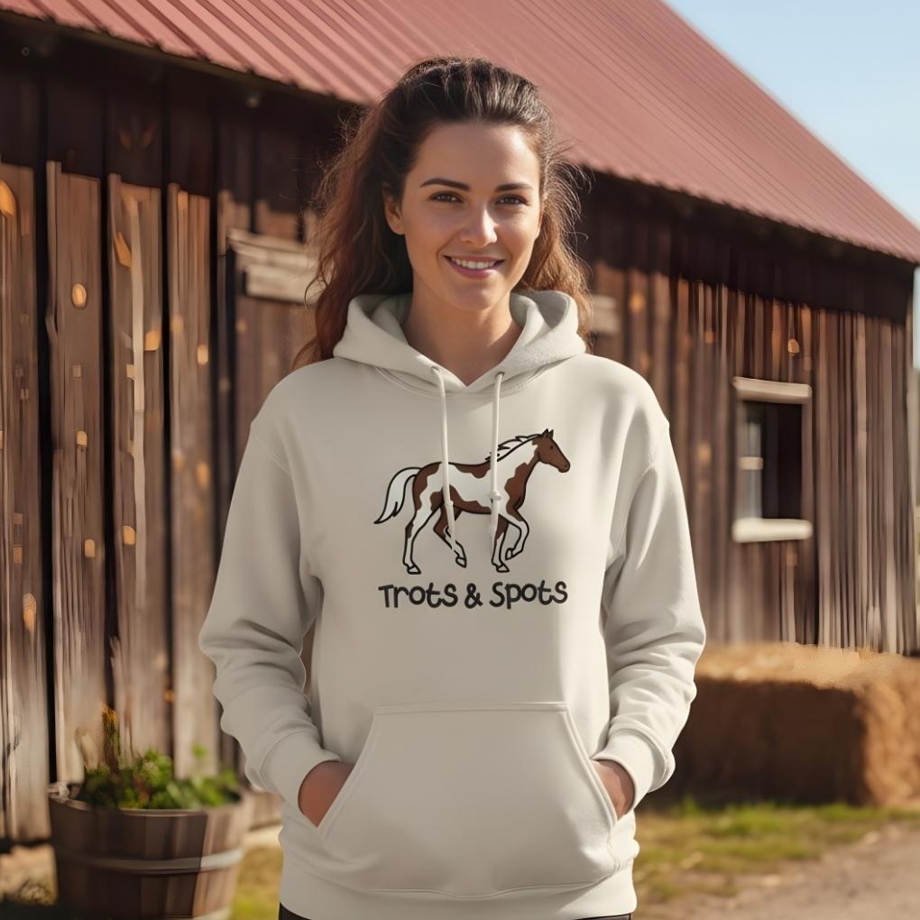 Woman wearing a hoodie with a horse design and text, standing in front of a wooden barn. Trots and Spots Hoodie, Trail Riding Tee for Horse Riders, Equestrian Hoodie for Barn Wear