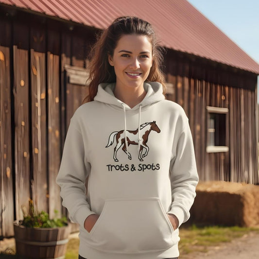 Woman wearing a hoodie with a horse design and text, standing in front of a wooden barn. Trots and Spots Hoodie, Trail Riding Tee for Horse Riders, Equestrian Hoodie for Barn Wear