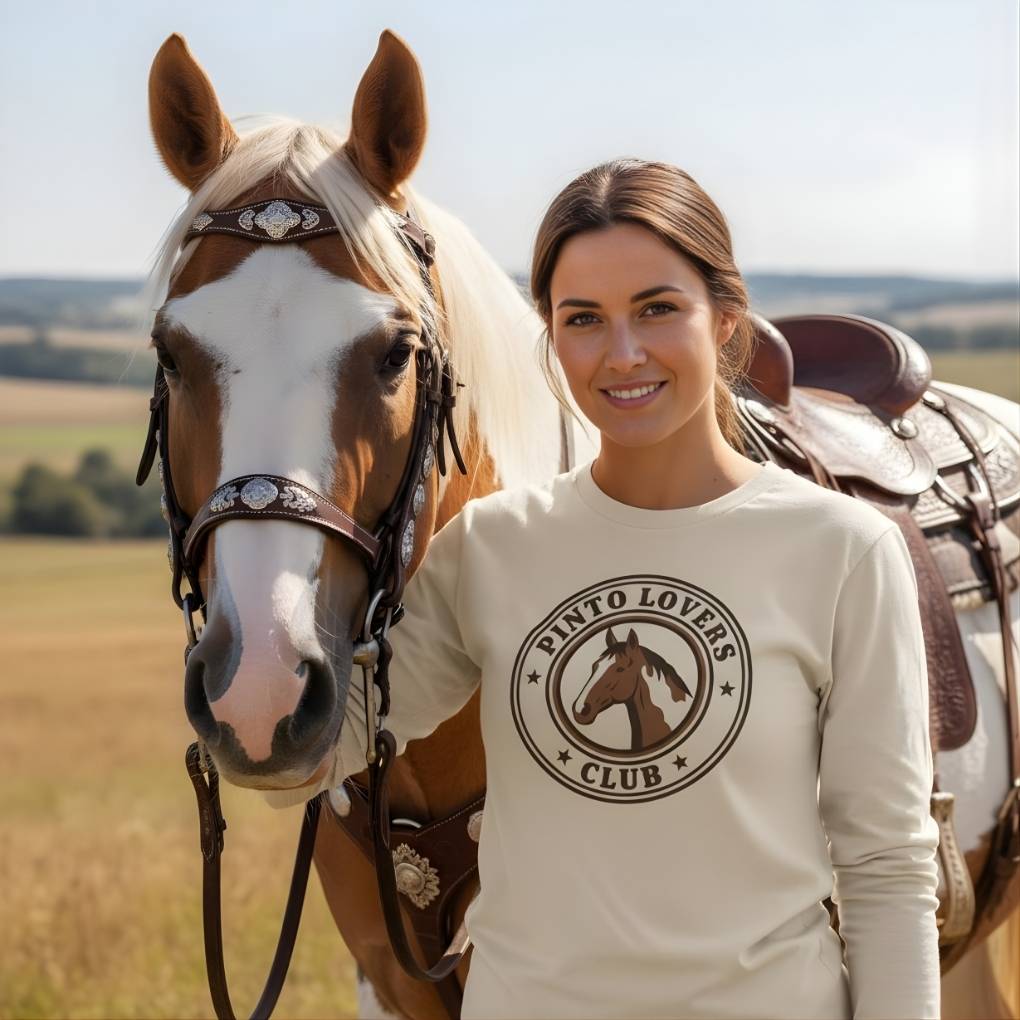 Woman wearing a 'Pinto Lovers Club' shirt standing next to a horse in an outdoor setting. Pinto Lovers Club Long Sleeve Tee for Pinto Horse Lovers, Long Sleeve Horse Tee