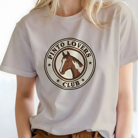 Person wearing a white t-shirt with 'Pinto Lovers Club' logo featuring a horse. Pinto Lovers Club T-Shirt for Pinto Horse Lovers, Trail Riding Tee for Horse Riders