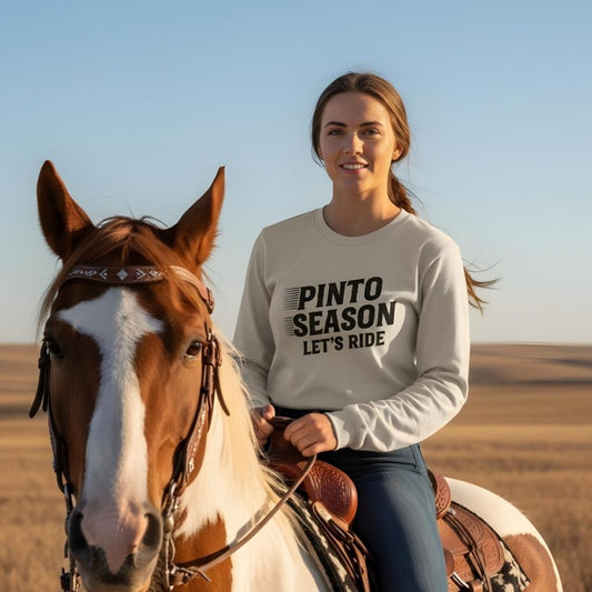 Woman in a 'Pinto Season Let's Ride' shirt standing next to a horse in an open field. Pinto Season Let's Ride Long Sleeve Tee for Pinto Lovers, Trail Riding Tee