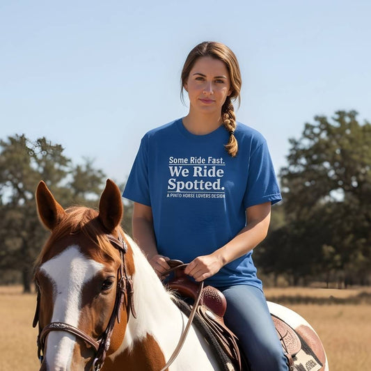Woman riding a horse wearing a blue t-shirt with text in an outdoor western setting. We Ride Spotted T-Shirt for Pinto Horse Lovers, Trail Riding Tee for Horse Riders