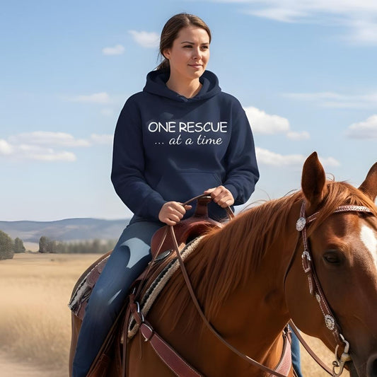 Woman riding a horse wearing a hoodie with 'ONE RESCUE ... at a time' text in an open field. One Rescue at a Time Hoodie, Just Giving Hoodie for Horse Lovers, Comfy Barn Wear