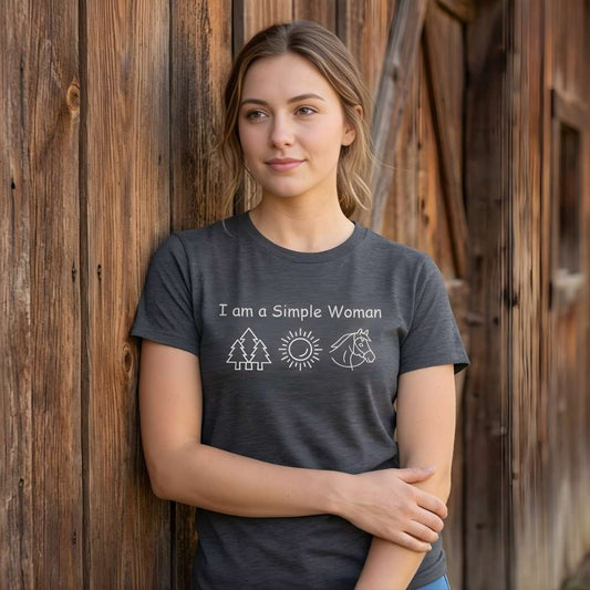 Woman wearing a t-shirt with 'I am a Simple Woman' text and nature symbols against a bar. I am a Simple Woman T-Shirt for Horse Lovers, Horse Riding Tee, Equestrian Wear