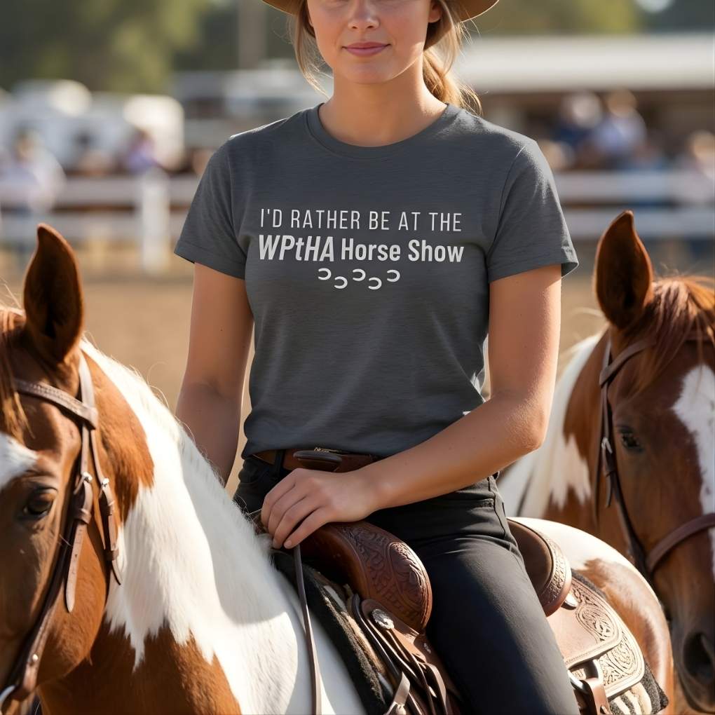 Woman on horseback wearing a t-shirt about horse shows with blurred background. Navy Blue I'd Rather be at the WPtHA Horse Show T-shirt for Pinto Horse Lovers, Trail Riding Tee, Charity fund raising tee for Wisconsin Pinto Horse Association
