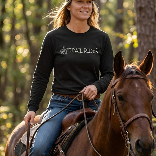 Woman riding a horse wearing a black 'Trail Rider' shirt in a forest setting, Trail Rider Long Sleeve Tee for Horse Riders, Trail Riding Sweatshirt Equestrian Wear