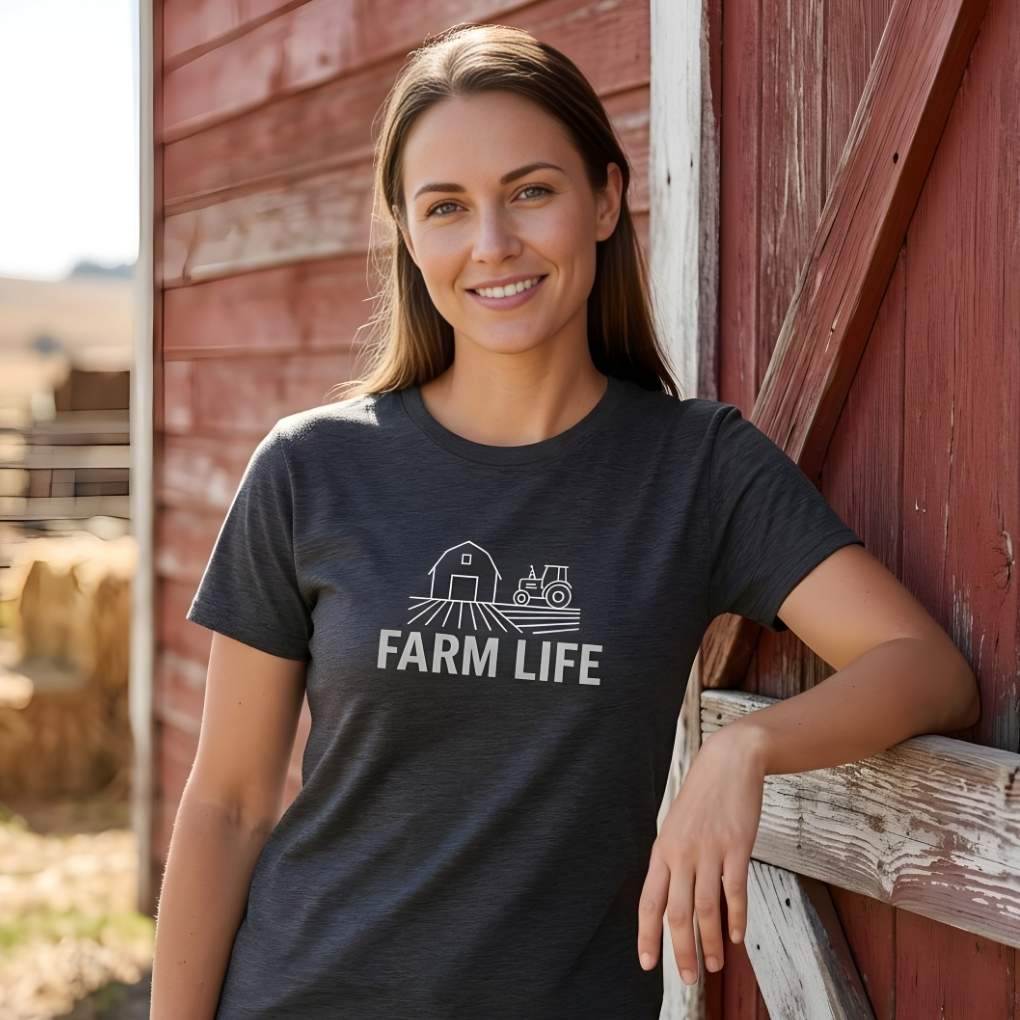 Woman wearing a 'Farm Life' t-shirt leaning against a red barn. Farm Life T-Shirt for Outdoor People, Horse Riders Tee, Barn Wear Tee