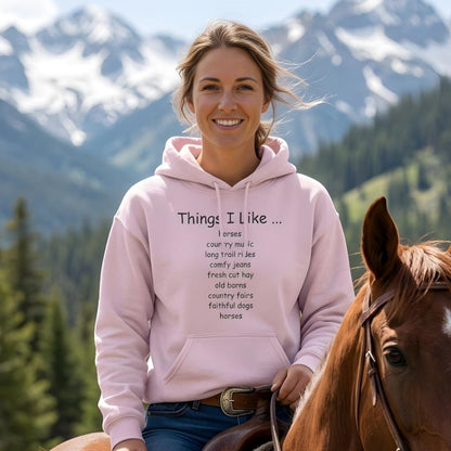 Woman wearing a pink hoodie with text, sitting on a horse with mountains in the background. Things I Like Hoodie for Horse Riders, Outdoor Wear, Trail Riding Hoodie Equestrian Apparel