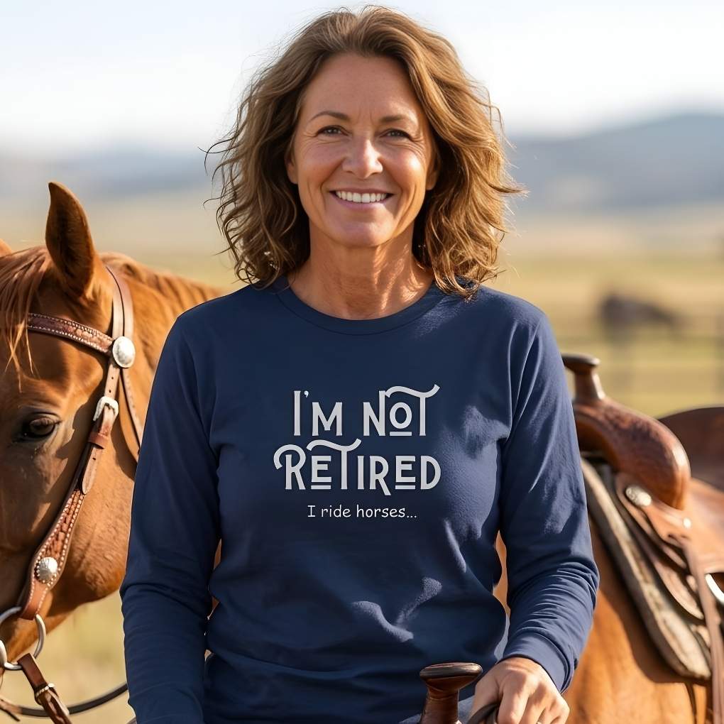 Woman wearing a navy blue sweatshirt with 'I'm not retired, I ride horses' text, standing next to a horse in a field. I'm Not Retired I Ride Horses Long Sleeve Tee for Horse Riders, Sweatshirt Trail Riding Top, perfect gift for horse lovers