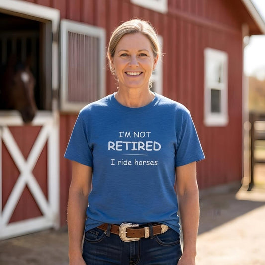Woman wearing a blue t-shirt with text standing in front of a red barn. I'm Not Retired I Ride Horses T-Shirt for Horse Lovers, Equestrian Tee for Trail Riding, perfect gift for horse lovers