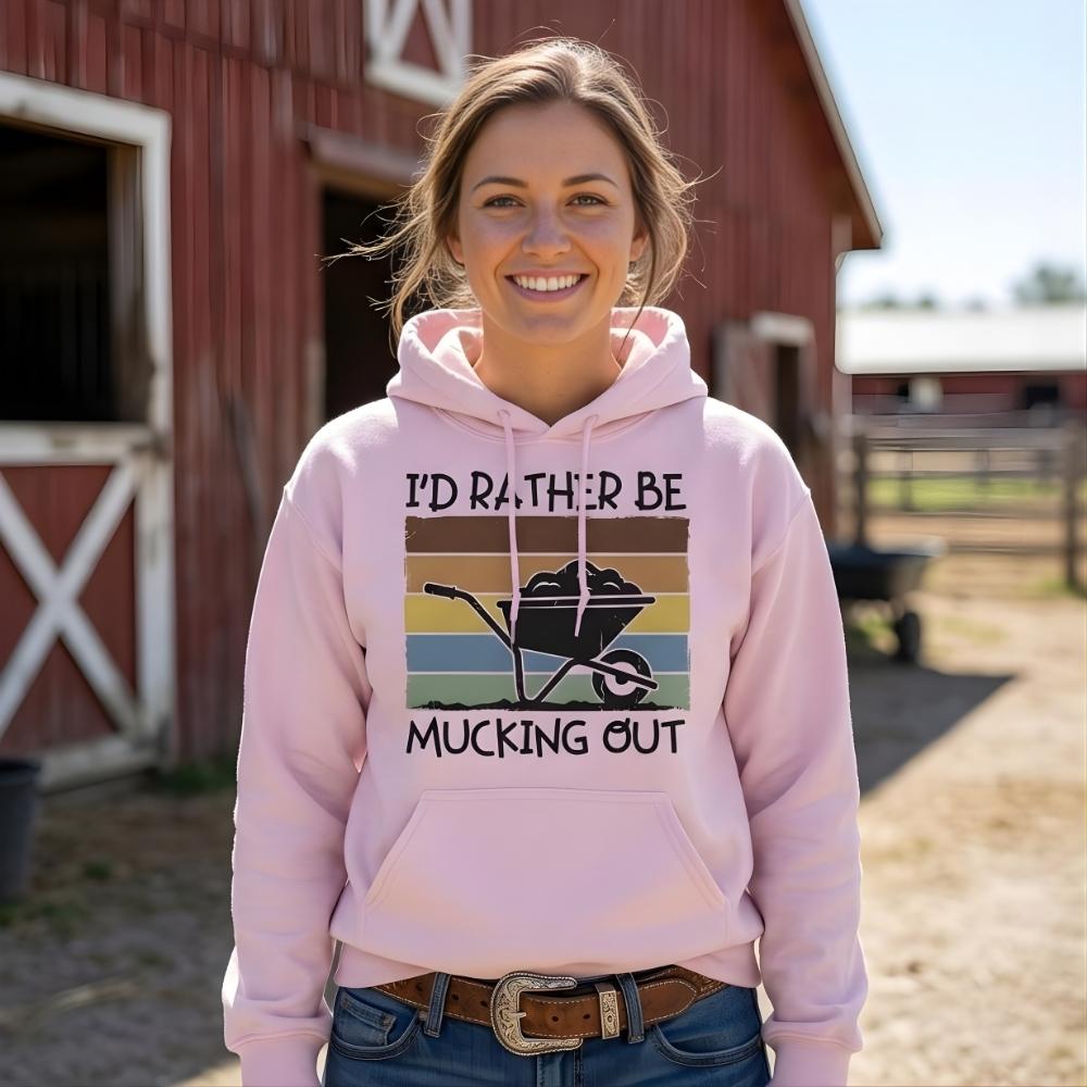 Woman wearing a pink hoodie with a farm-themed design in front of a barn. I'd Rather be Mucking Out Hoodie for Horse Lovers, Barn Yard Hoodie, perfect gift for horse lover