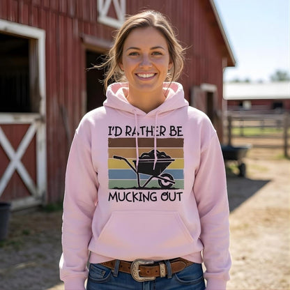 Woman wearing a pink hoodie with a farm-themed design in front of a barn. I'd Rather be Mucking Out Hoodie for Horse Lovers, Barn Yard Hoodie, perfect gift for horse lover