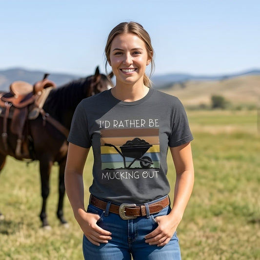Woman wearing a t-shirt with a horse-themed graphic and text, standing in a field with horses in the background.  I'd Rather be Mucking Out T-Shirt for Horse Lovers, Barn Yard Tee, great gift for horse lover