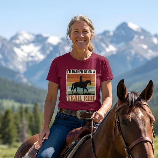 Woman riding a horse with mountains in the background wearing a t-shirt with a trail ride graphic. I'd Rather be on a Trail Ride T-Shirt for Horse Lovers, Trail Riding Tee. Perfect gift for horse lover. 