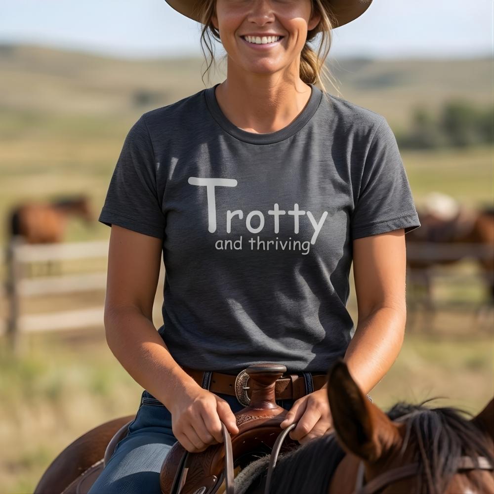 Person riding a horse wearing a t-shirt with 'Trotty and thriving' text in a rural setting. Trotty and Thriving T-Shirt for Horse Lovers, Trail Riding Tee Equestrian Top, perfect gift for horse lovers, mothers day gift