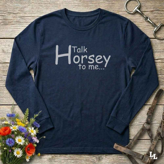 Navy blue long-sleeve shirt with 'Talk Horsey to me...' text on a wooden surface with floral and equestrian-themed items.