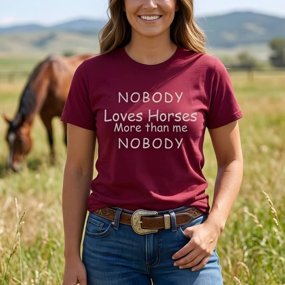 Person wearing a maroon t-shirt with a humorous horse-themed quote in a field with a horse. Nobody Loves Horses More than Me T-Shirt for Horse Lovers, Unisex Trail Riding Shortie. Perfect present for horse riders, xmas gift for horse lovers