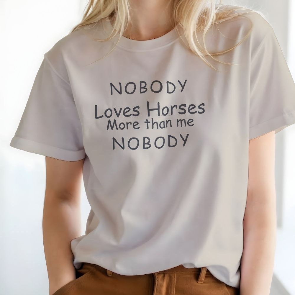 Person wearing a white t-shirt with humorous text design. Nobody Loves Horses More than Me T-Shirt for Horse Lovers, Unisex Trail Riding Shortie. Perfect present for horse riders, xmas gift for horse lovers