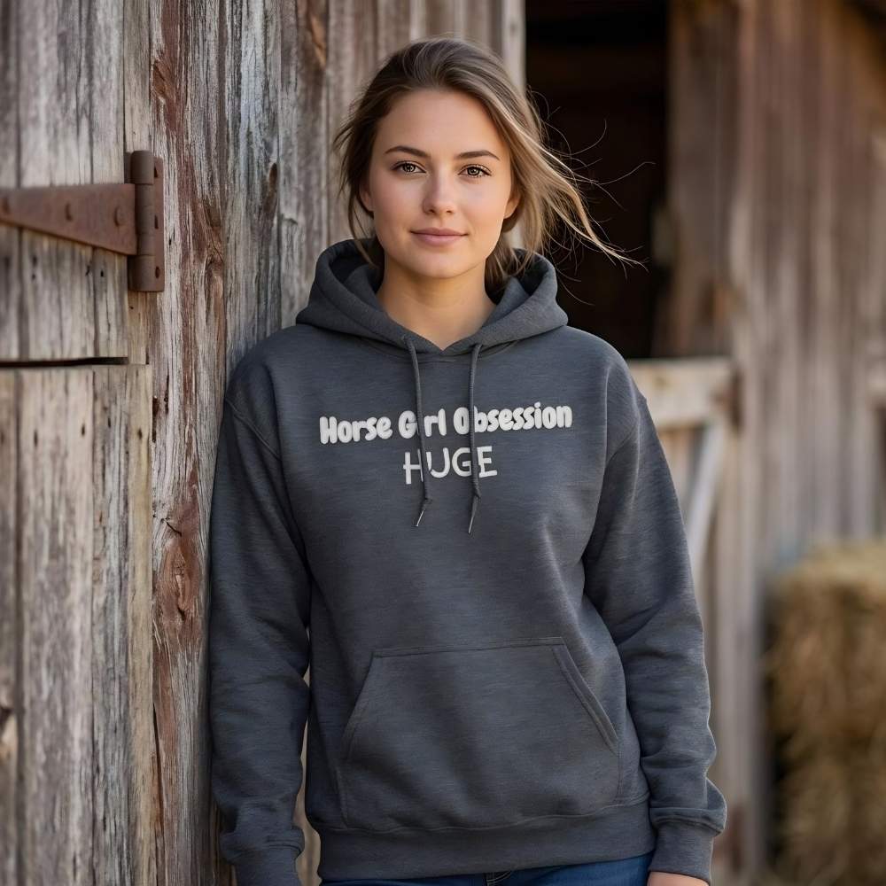 Woman wearing a gray hoodie with text standing in front of a wooden barn. Horse Girl Obsession Hoodie for Horse Lovers, Cozy Equestrian Hoodie for Barn Wear, perfect gift for horse riders, mothers day gift for horse lovers, Xmas gift for horse lovers and riders