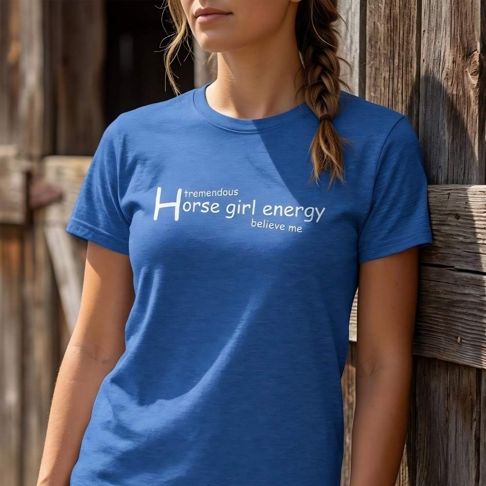 Person wearing a blue t-shirt with text standing against a wooden barn. Horse Girl Energy T-Shirt gift for Horse Riders, Horse Lover Tee, Trail Riding Top. Perfect gift for horse lover, gift for mothers day, xmas gift for horse riders.