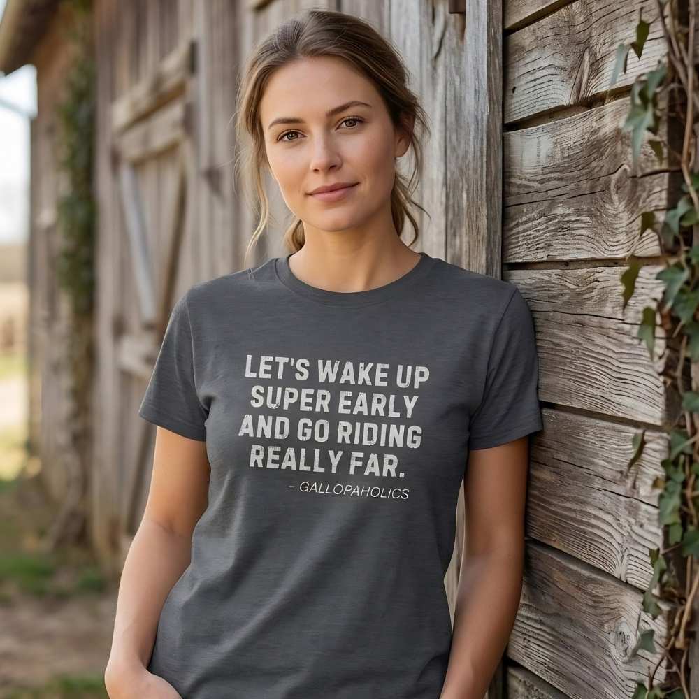 Woman wearing a t-shirt with a humorous quote about early morning rides, standing against a wooden barn. Let's Wake Up Super Early T-Shirt for Horse Riders. Equestrian wear trail riding Tee. Perfect gift for horse lover, birthday present for horse rider, mother's day present, father's day present.