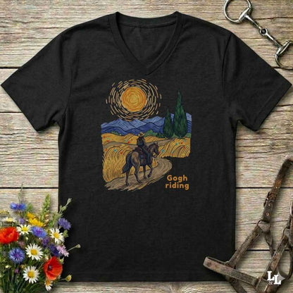 black v-neck tee with van gogh inspired design and the words Gogh Riding, lying on barn style floorboards with flowers and horse halter and horse bit