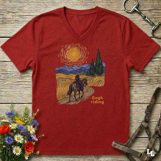 Red v-neck tee with van gogh inspired design and the words Gogh Riding, lying on barn style floorboards with flowers and horse halter and horse bit