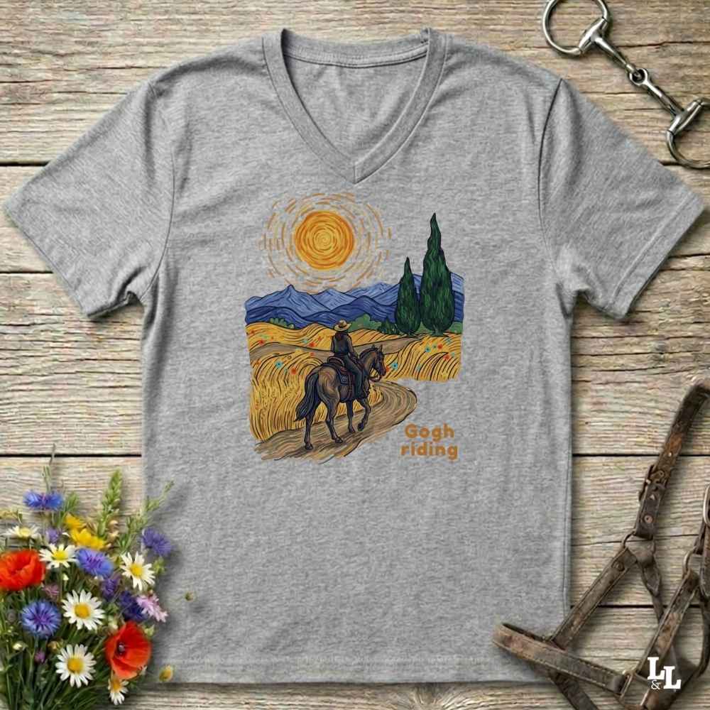 grey v-neck tee with van gogh inspired design and the words Gogh Riding, lying on barn style floorboards with flowers and horse halter and horse bit