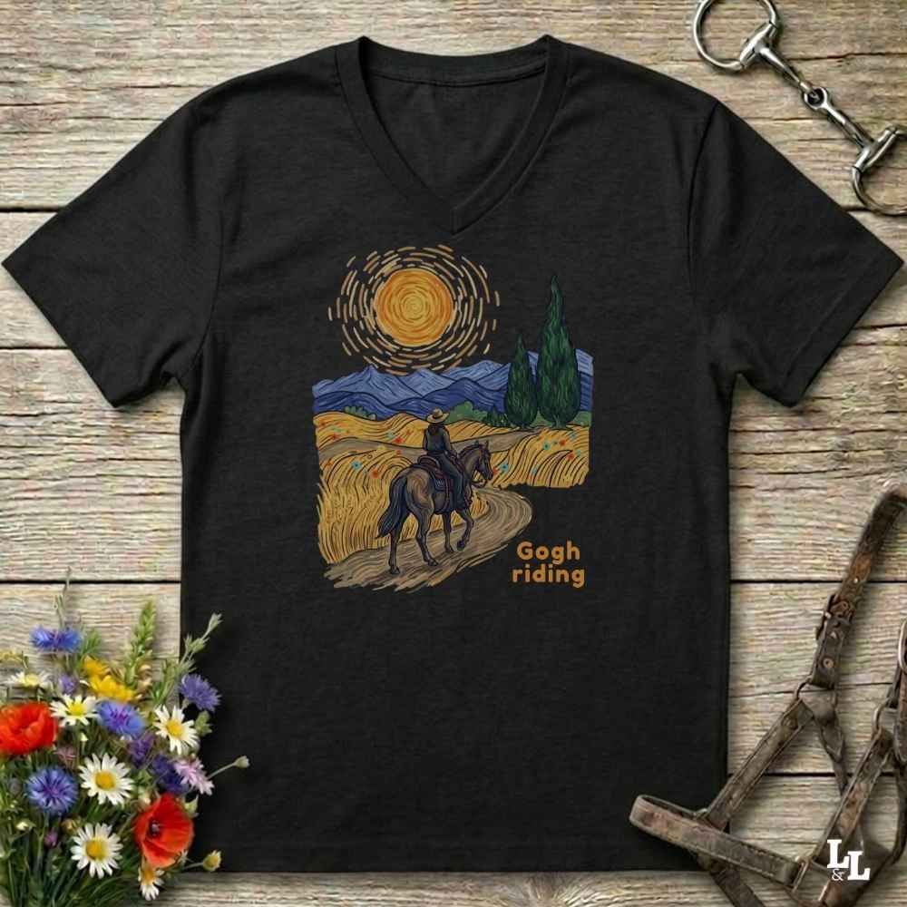 black v-neck tee with van gogh inspired design and the words Gogh Riding, lying on barn style floorboards with flowers and horse halter and horse bit