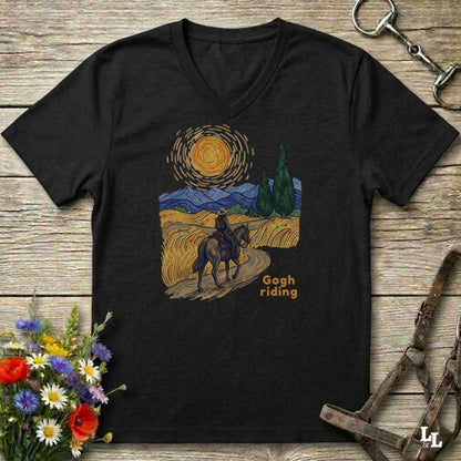 black v-neck tee with van gogh inspired design and the words Gogh Riding, lying on barn style floorboards with flowers and horse halter and horse bit