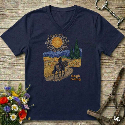 blue v-neck tee with van gogh inspired design and the words Gogh Riding, lying on barn style floorboards with flowers and horse halter and horse bit
