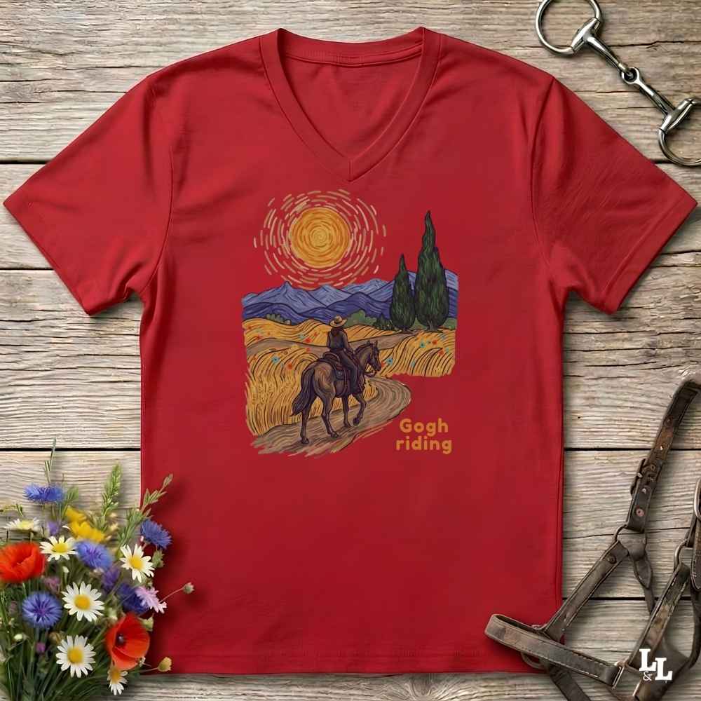 Red v-neck tee with van gogh inspired design and the words Gogh Riding, lying on barn style floorboards with flowers and horse halter and horse bit