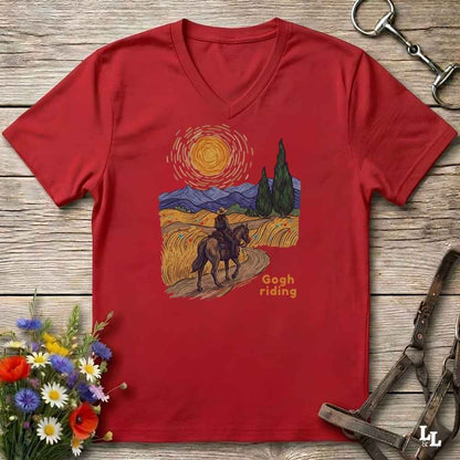 Red v-neck tee with van gogh inspired design and the words Gogh Riding, lying on barn style floorboards with flowers and horse halter and horse bit
