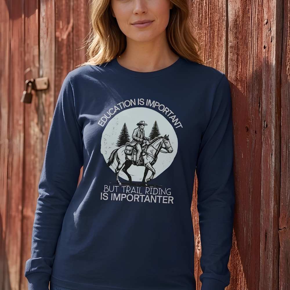 Person wearing a navy blue sweatshirt with a graphic and text in front of a wooden barn. Education is Important Long Sleeve Tee for Horse Lovers, Equestrian Wear, horse girl shirt, horse mom shirt, horse lover, horse girl, Funny horse lover gifts, Funny horse shirts, Horse girl gifts, Equestrian graphic tees, fathers day gift, Sarcastic horse shirt