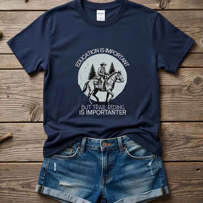 Navy blue t-shirt with graphic design and text on a wooden surface, paired with denim shorts. Education is Important T-Shirt for Horse Lovers, Equestrian Wear Short Tee, horse girl shirt, horse mom shirt, horse lover, horse girl, Funny horse lover gifts, Funny horse shirts, Horse girl gifts, Equestrian graphic tees, fathers day gift, Sarcastic horse shirt