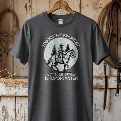 Gray t-shirt with a graphic of a person on a horse and text, hanging in a barn. Education is Important T-Shirt for Horse Lovers, Equestrian Wear Short Tee, horse girl shirt, horse mom shirt, horse lover, horse girl, Funny horse lover gifts, Funny horse shirts, Horse girl gifts, Equestrian graphic tees, fathers day gift, Sarcastic horse shirt