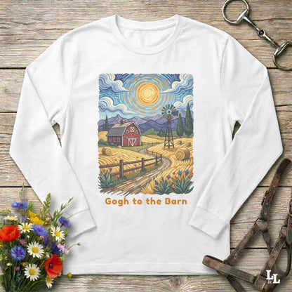 A white long-sleeve t-shirt with a colorful, stylized art print of a farm scene in a Van Gogh-inspired style, featuring a red barn, yellow fields, and a windmill, with the text 'Gogh to the Barn' printed below. The shirt is displayed flat on a rustic wooden background with decorative props including flowers, a horse bit, and a leather bridle.