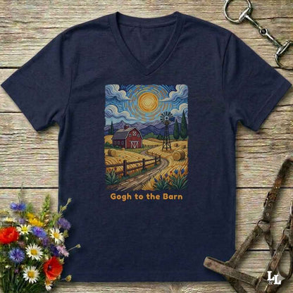 A navy blue V-neck t-shirt laid flat on a rustic wooden surface, featuring a colorful art print of a farm scene with a barn, sun, and the text 'Gogh to the Barn'.