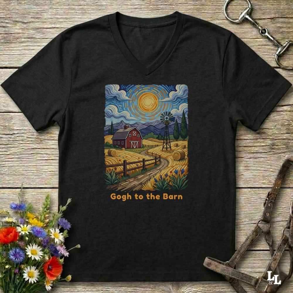 black V-neck t-shirt laid flat on a rustic wooden surface, featuring a colorful Van Gogh-inspired barn scene graphic with the text 'Gogh to the Barn'. The shirt is styled with equestrian props (reins and a bit) and a small bouquet of wildflowers.