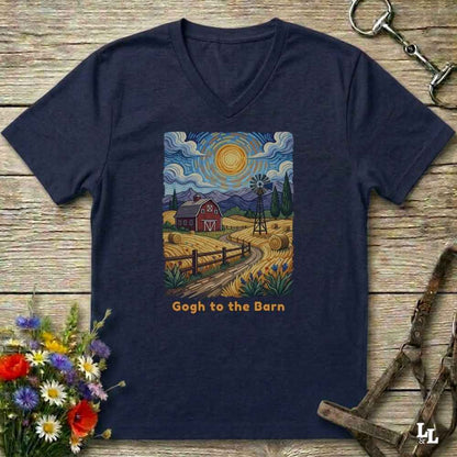 blue V-neck t-shirt laid flat on a rustic wooden surface, featuring a colorful Van Gogh-inspired barn scene graphic with the text 'Gogh to the Barn'. The shirt is styled with equestrian props (reins and a bit) and a small bouquet of wildflowers.
