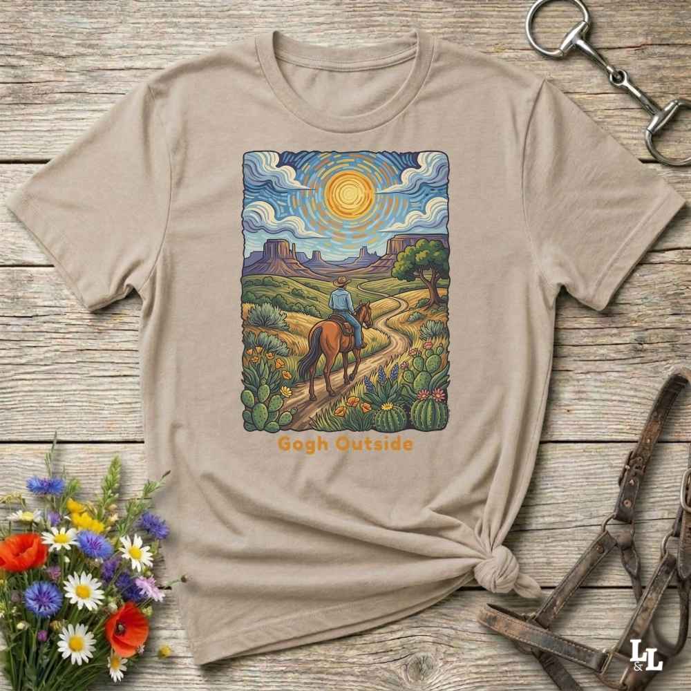 Beige t-shirt with a desert scene graphic and 'Gogh Outside' text on a wooden surface with flowers and a key. Perfect gift for horse lovers.