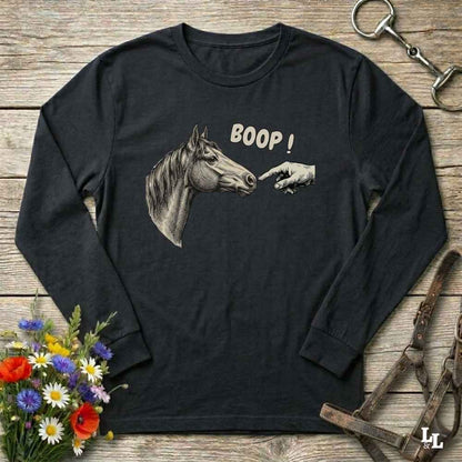 Black long-sleeve shirt with horse graphic and 'BOOP!' text on a wooden surface with floral and equestrian accessories.